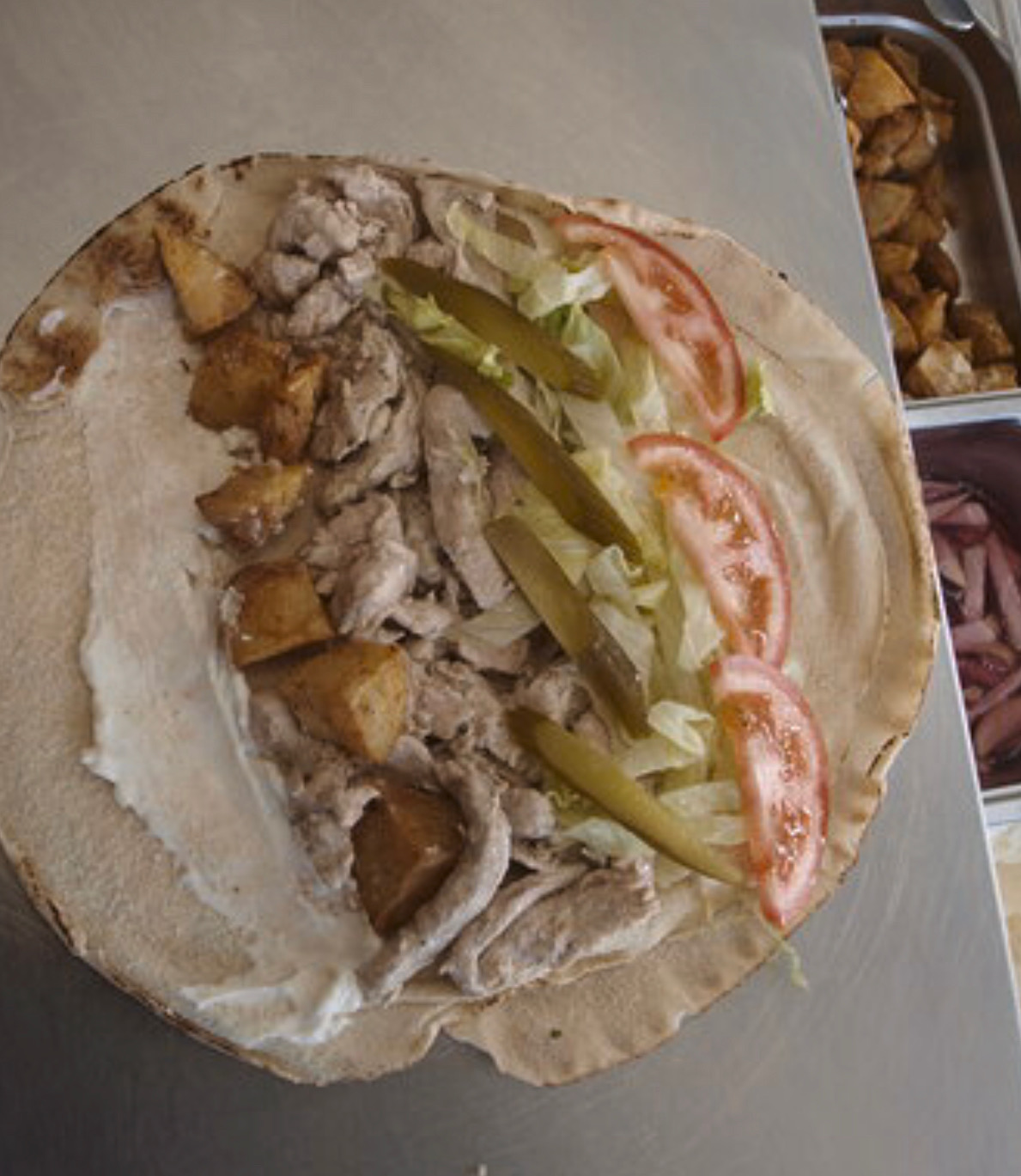 En cuisine — préparation d'un chawarma sur pain libanais, crème d'ail et pommes de terre