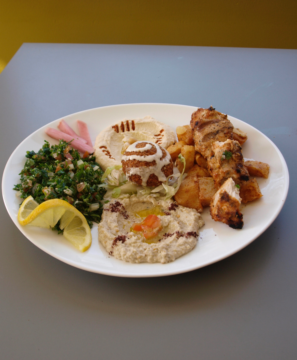 Assiette O'Mezza — poulet mariné grillé, pommes de terre sautées, hommos, moutabbal, taboulé et falafel
